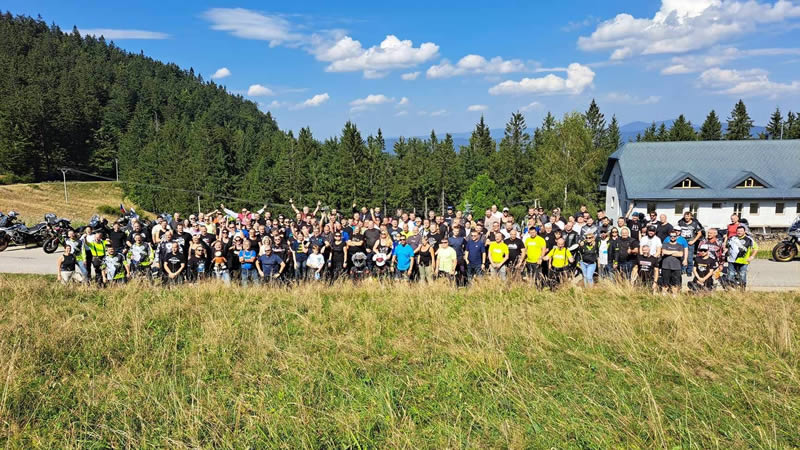 Skupinové foto příznivců CFMOTO - na louce za slunného dne