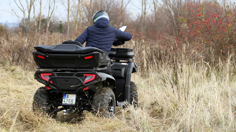 Zadní pohled na čtyřkolku CFMOTO Gladiator jedoucí na poli během podzimu