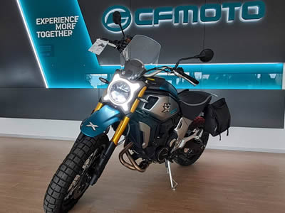 CFMOTO 700CL-X Adventure - pohled na stojící motorku v modré a stříbrné barvě s černým koženým sdedlem